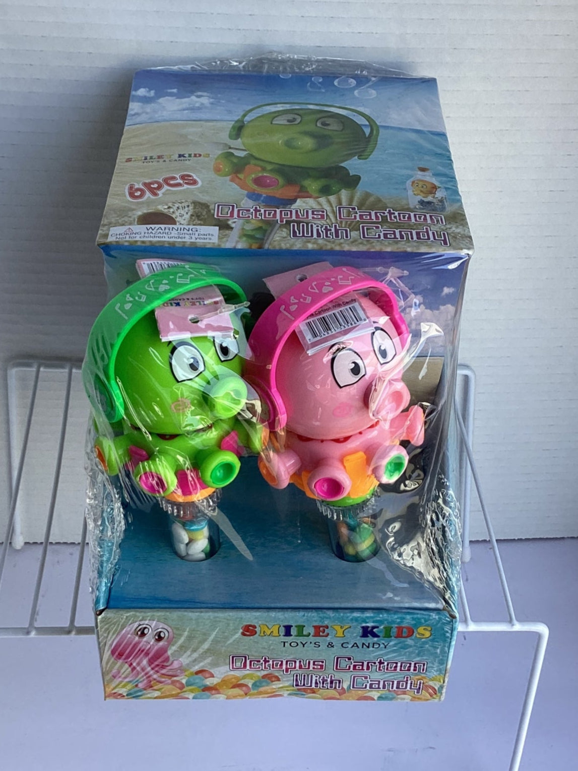 Two toy octopuses in packaging on a white stand with a white background